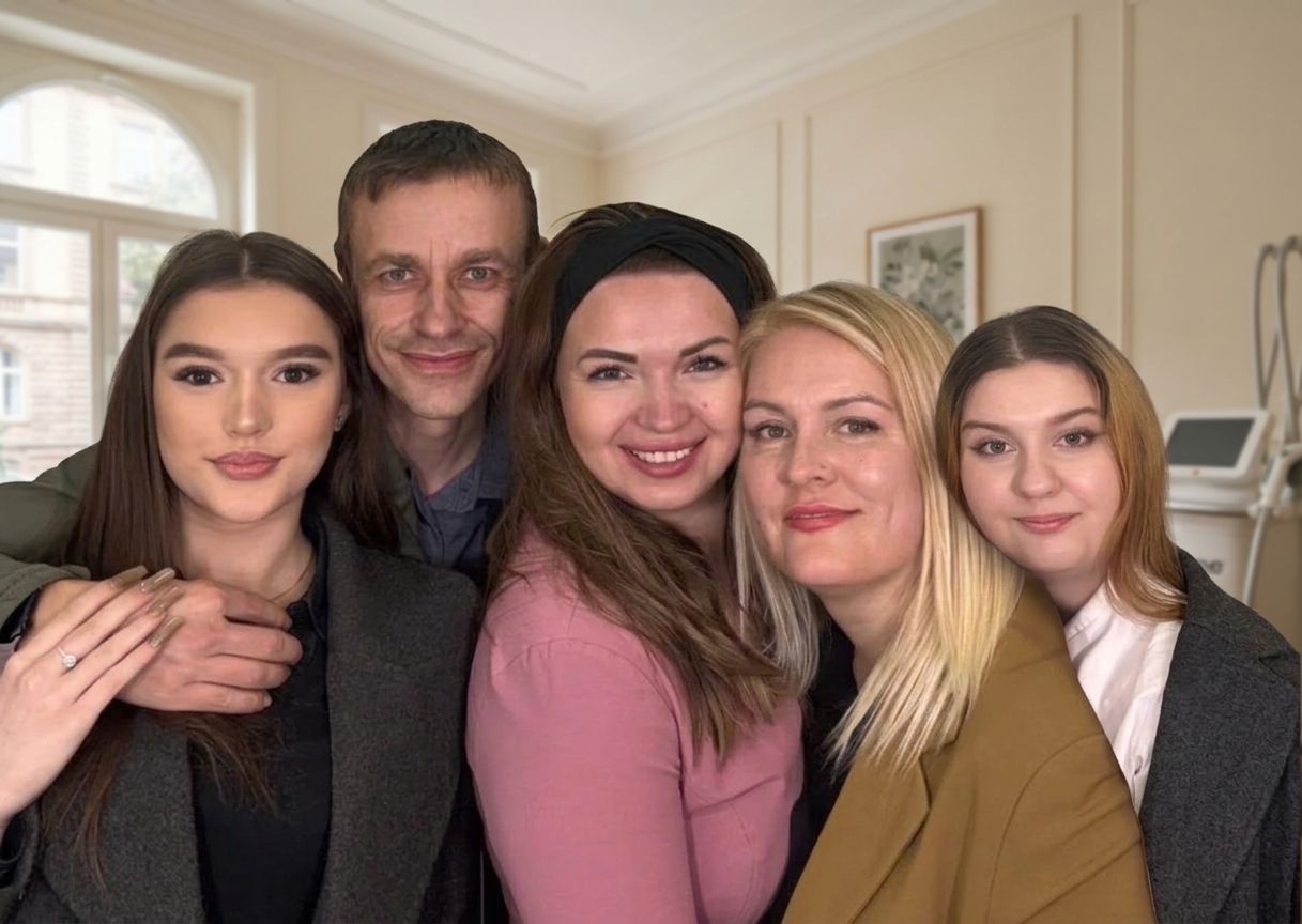 Teamporträt im Ariona-Beauty-Studio Kassel: fünf zufriedene Menschen, darunter Elena und Arina, vor cremefarbenen Wänden, Bogenfenster und Icoone-Laser-Gerät