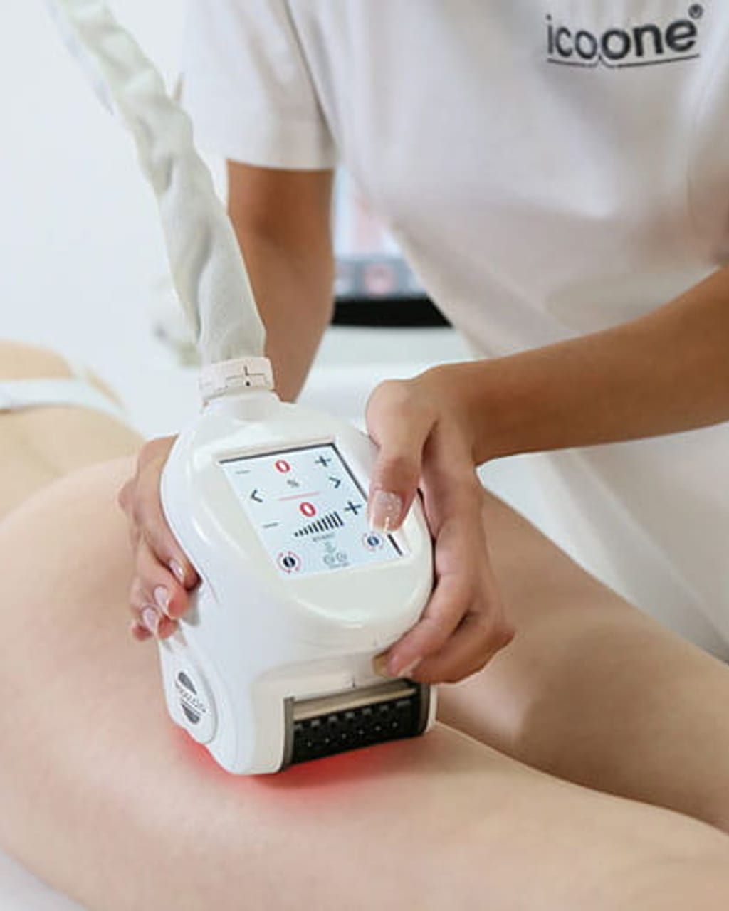 Detailaufnahme einer Body-Sculpting-Behandlung mit Icoone Laser im Ariona-Beauty-Studio Kassel: zwei Hände in weißen Handschuhen führen beide Roboderm-Handstücke mit grünen LED-Statusringen über den entspannten Bauch der Kundin