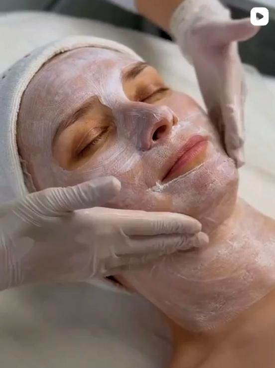 Klassische Gesichtsbehandlung im Ariona-Beauty-Studio Kassel: die Kosmetikerin trägt mit beiden behandschuhten Händen eine cremige Pflegemaske auf das entspannte Gesicht der Kundin auf